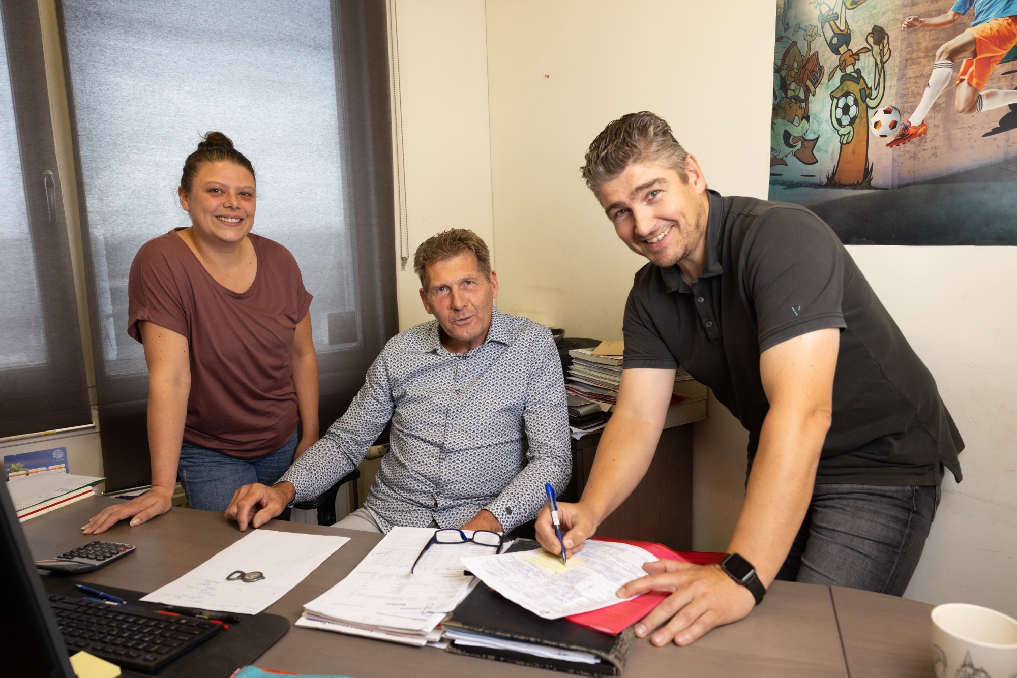 Rick Pluijmers met collega's aan het bureau op kantoor