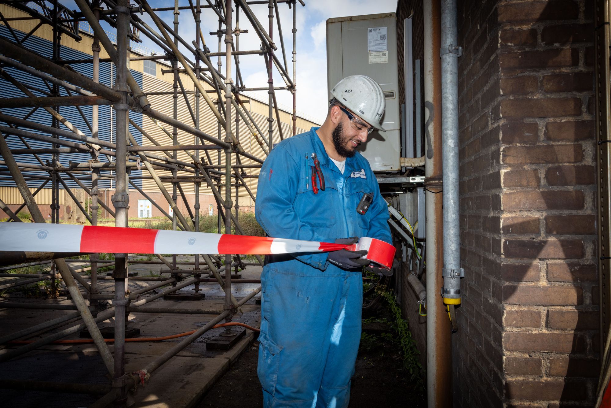 Monteur van Plubos bij een afzetlint op een industrieterrein