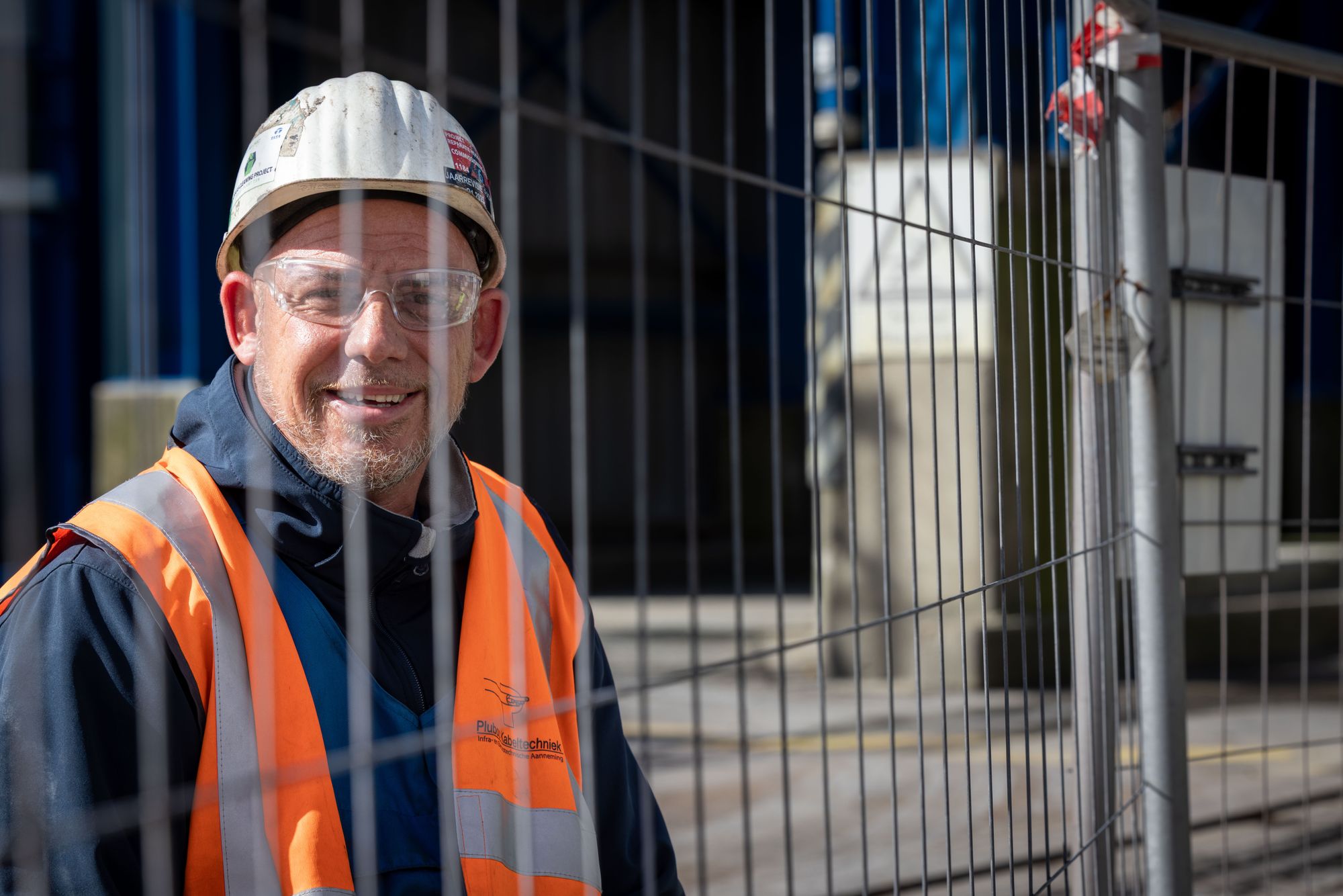 Lachende monteur van Plubos met helm en veiligheidsbril