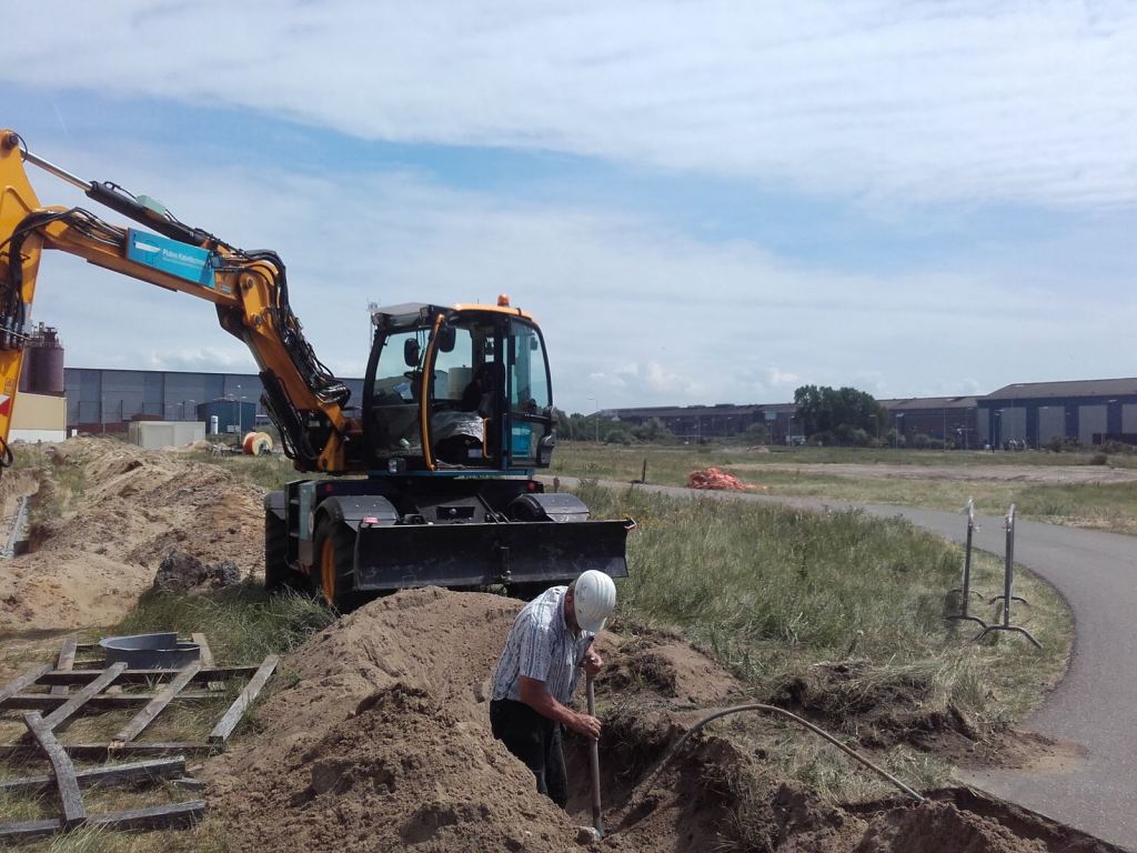 Monteur in de sleuf naast de graafmachine