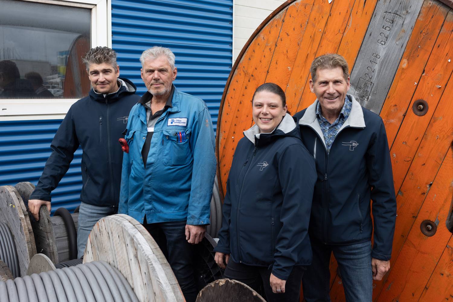 Vier mensen van Plubos voor grote kabelhaspels bij het bedrijfspand