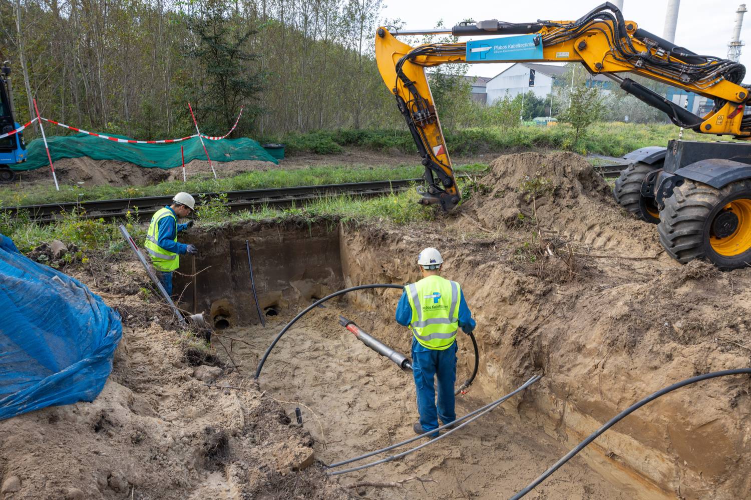Ploeg bij een ontgraven kabeltracé met een graafmachine